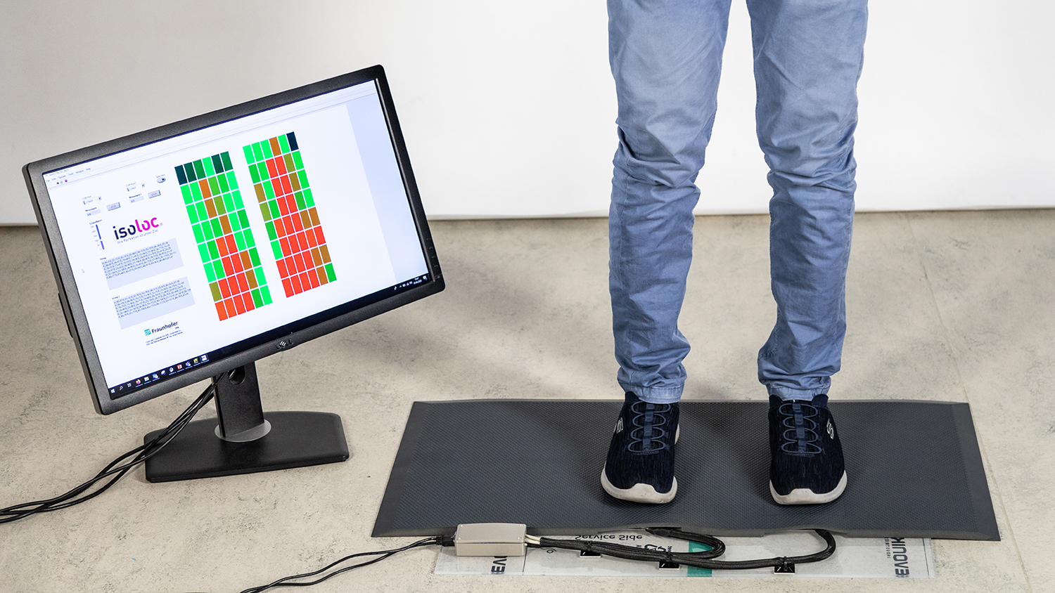 Proband steht auf Sensormatte; Bildschirm zeigt an, welche Bereiche der Füße gerade belastet werden